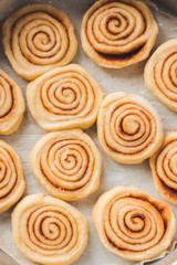 Delicious homemade raw cinnamon rolls bun dough in rectangle shaped baking tray on the white baking paper. Top view. Interesting pattern