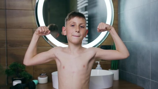 Attractive nude teenager posing on camera and showing his muscles in the bathroom