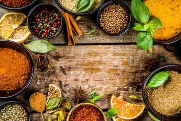Set of Spices and herbs for cooking. Small bowls with colorful  seasonings and spices - basil, pepper, saffron, salt, paprika, turmeric. On rustic wooden plank table background, top view copy space