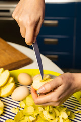 Woman cooking and cutting apple on wooden cutting board. Preparing healthy food.
