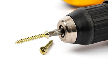 closeup of a yellow battery operated drill with screwdriver bit and phillips wood screws on the bit isolated on white 
