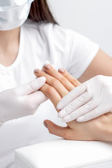 Obraz na płótnie Canvas Manicurist holding woman's hand with beige polish on nails, close up.