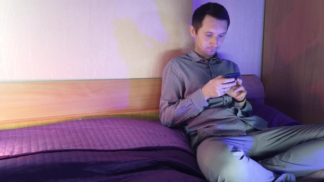 A man at home sits in a phone and plays in an online casino, emotions from the win
