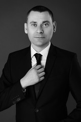 Portrait of an attractive young businessman in black background wearing suit and necktie. Classic style. Studio shot