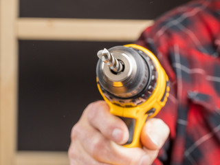 close up of a worker holding an electric drill with a high speed metal drill bit pointing at the...