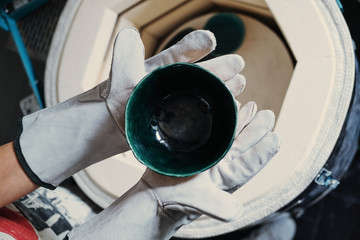 Clay master Hands wearing gloves holding cup from ceramic kiln