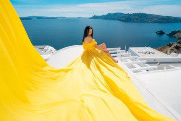 Europe cruise travel summer vacation luxury tourist destination european woman relaxing in Oia, Santorini, Greece in yellow dress aerial on the roof