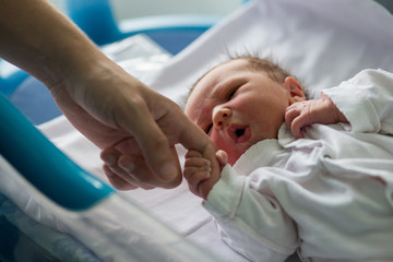 Beautiful newborn baby boy, laying in crib in prenatal hospital