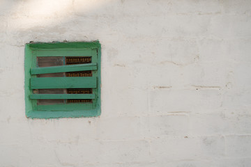 Small window on a white wall of an old house background