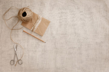 Top view image fashion designer background concept.Flat lay sewing scrapbooking accessory.Scissors, skein of twine on brown linen fabric at home studio. Space for design mockup