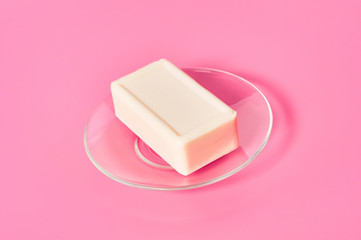Soap for hand washing on glass saucer on pink desk in bathroom. Hygiene concept