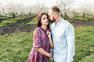 Loving couple hugging and walking. Lovestory in a blooming apple garden