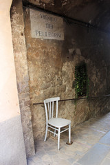 Fototapeta na wymiar A deserted street with white chair in Italy