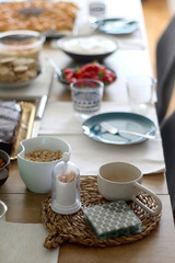 Table setting with colorful dishes and various food: crackers, hummus, homemade bread, cake, strawberries and whipped cream. Selective focus.
