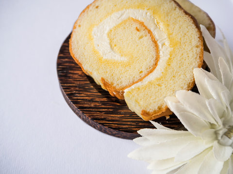 Vanila coconut cream jam roll are on the wooden plate and  decorated white flower and on isolated white background.