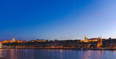 Fototapeta na wymiar Cityscape of Budapest and Danube river in sunset time. Blue sky and yellow lights of urban city with famous landmarks. Tourism concept of old capital in Hungary.