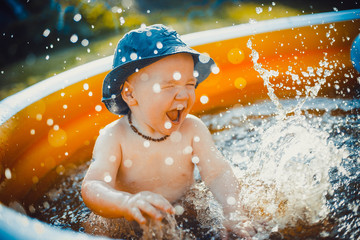 Little boy having fun and splashes water in orange pool