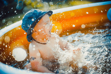 Little boy having fun and splashes water in orange pool