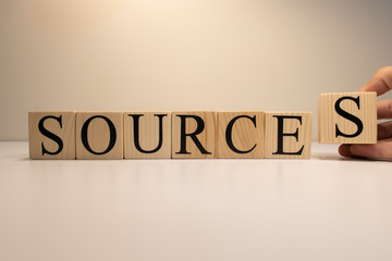 Sources text from wooden cubes. On a white background. Close up.