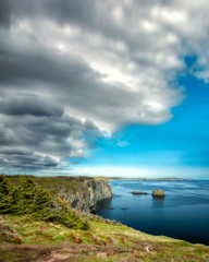Pristine coastal seascape with soft clouds and sea stacks in beautiful clear blue water. Skerwink trail located in Port Rexton, Newfoundland Canada. 