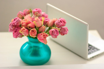 silver laptop on a table with a bouquet of roses