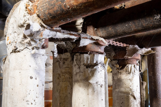 Dangerous Broken Asbestos Wrap Insulation On Rusty Heating System Pipes