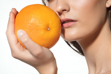 Sun in hands. Close up of beautiful young woman with big grapefruit on white background. Concept of cosmetics, makeup, natural and eco treatment, skin care. Shiny and healthy skin, fashion, healthcare
