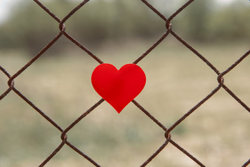 Red heart on a chain link fence.