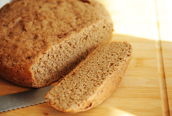 Freshly baked homemade rye-wheat whole grain bread. Sliced slice of bread on the board