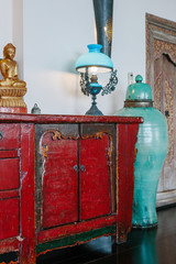 Old cupboard,  Buddha statue, lamp, large vase in retro interior design .