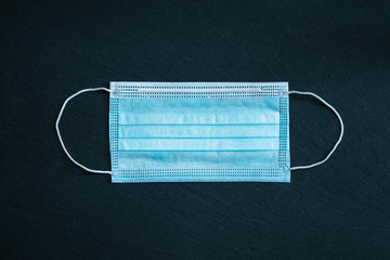 Surgical, disposable mask, isolated on a black stone textured background