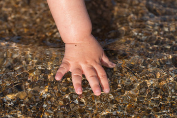 hands of a white child playing in the shallow sea
