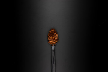 coffee powder on black spoon, black background. food and drinks concept wallpaper.