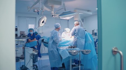 Operation room with specialists. Teamwork of surgeons performing operation on the background of modern equipment in private clinic.