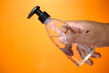 hand holding sanitizer against orange background, Close up 