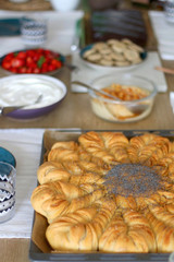 Various food served on a table: homemade pull apart bread, hummus, cream, crackers and strawberries. Selective focus.