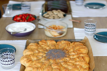 Various food served on a table: homemade pull apart bread, hummus, cream, crackers and strawberries. Selective focus.
