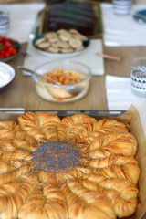 Various food served on a table: homemade pull apart bread, hummus, cream, crackers and strawberries. Selective focus.