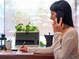 Young Woman Working At Home in a Relaxed Atmosphere Talking on the Phone.