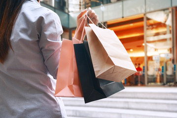 Woman carrying a shopping bag on her right hand is walking into department store that is open for...