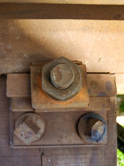 A rusted railroad bridge on a sunny day with cloudy blue sky on the background.