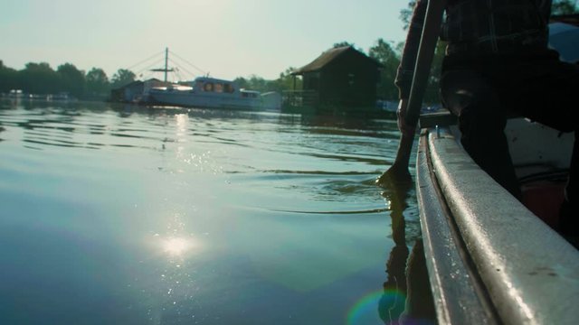 Close up of man in old white boat rowing in sunrise