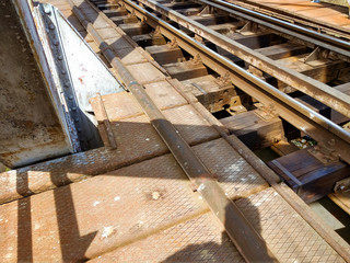 A rusted railroad bridge on a sunny day with cloudy blue sky on the background.