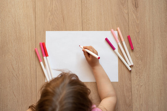 Small girl drawing picture on the paper with crayons