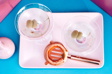 Close up top view, details of dry martini cocktail with olives. Alcoholic cocktail drinks on pink and blue background