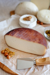 Cheese mix on a wooden plate decorated with grapes, nuts, salad and olives with cheese knifes 