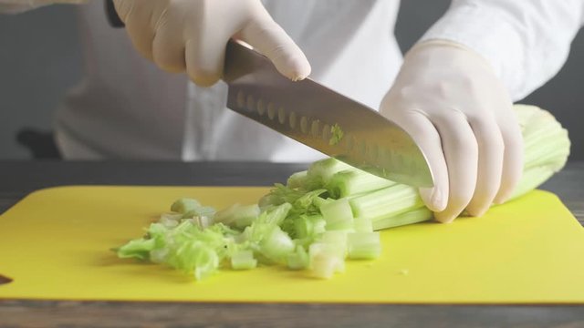 a woman prepares slices on a cutting board ingredients for a celery smoothie and puts them in a blender bowl