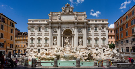 Fototapeta na wymiar The baroque masterpiece of the Trevi Fountain in Rome, one of the most popular tourist attractions in the city, on a summer afternoon against a blue sky.