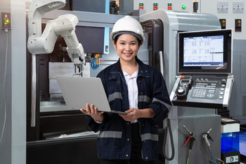 Naklejka na ściany i meble Maintenance female engineer using laptop computer control automatic robotic hand with CNC machine in smart factory, Industry 4.0 concept