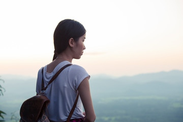 Beautiful Asian female tourists standing on top of the mountain during sunset,Women stand alone with nature, distance, social concept,Corona virus(Covid19)